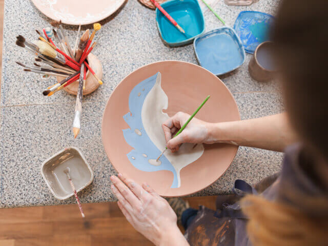 Mujer pintando una pieza de cerámica